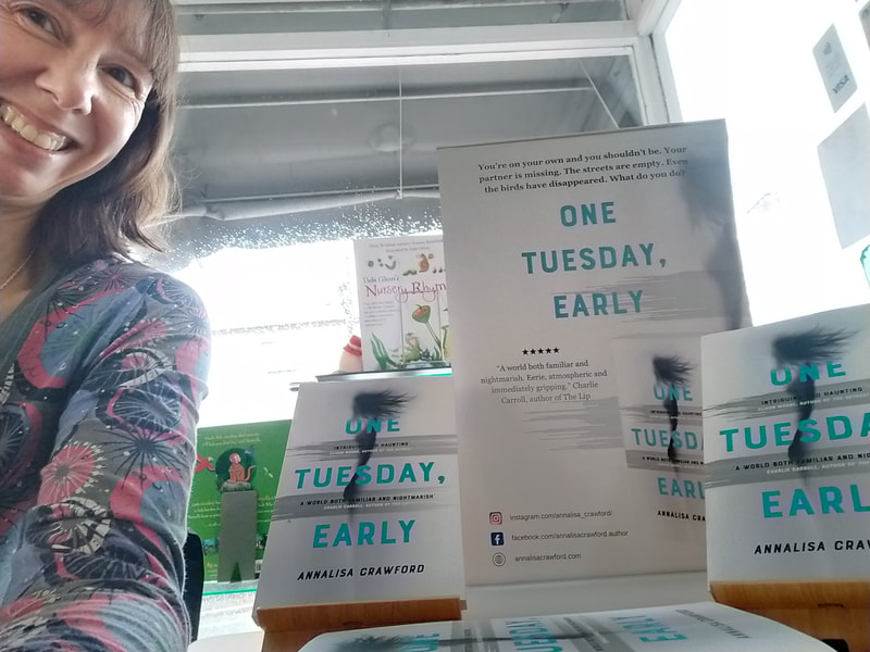 Picture shows a display of copies of One Tuesday, Early and the author is grinning in the left hand corner.