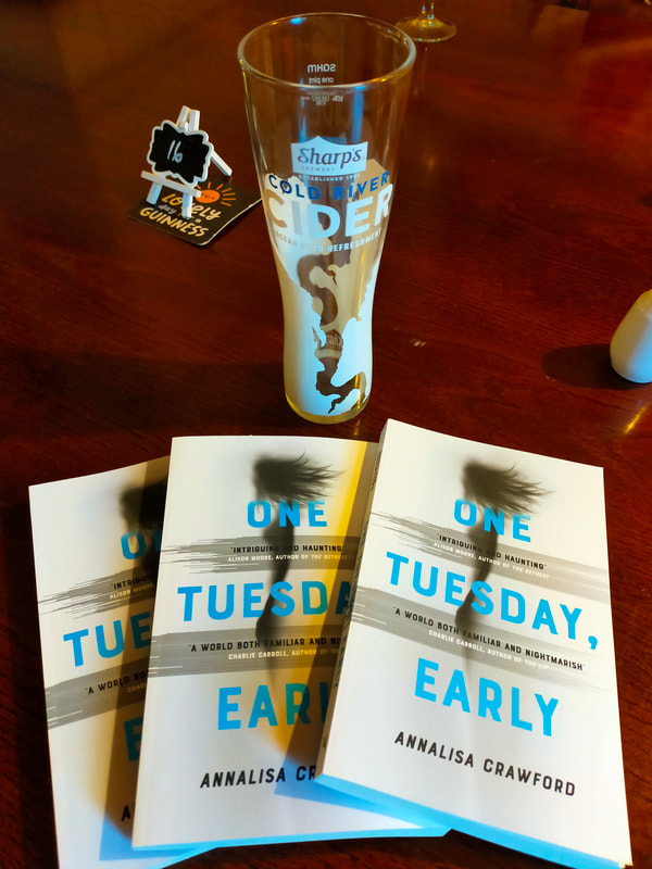 Picture shows three copies of the novel on a table with a half-drunk pint of cider.